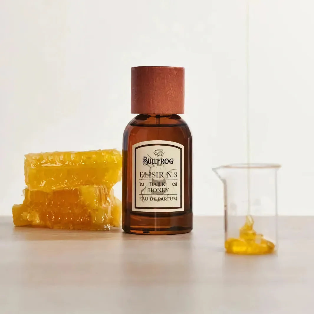Bullfrog Elisir N.3 Dark Honey Eau de Parfum 100 ml bredvid honungskaka och glasbehållare – exklusiv parfym från Bullfrog