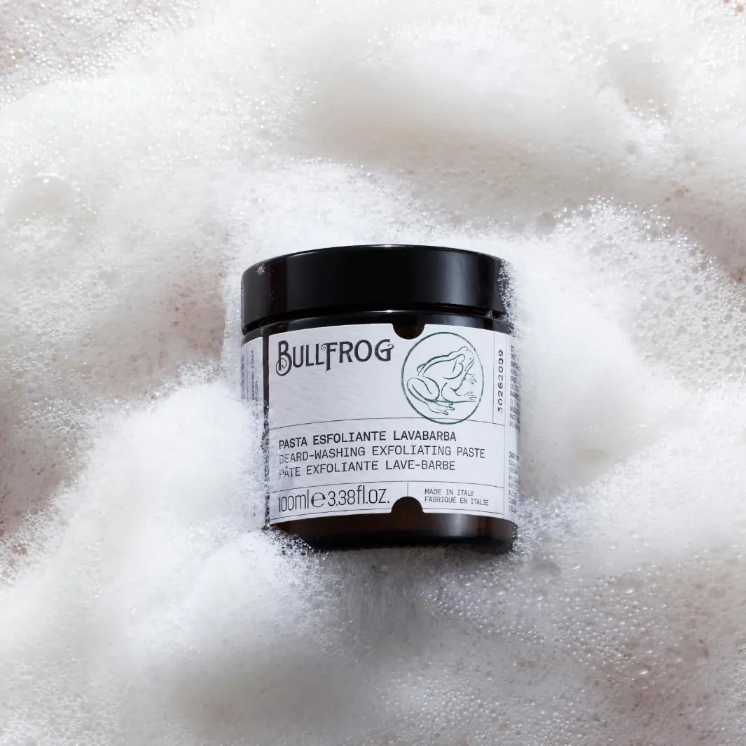 Bullfrog Beard-Washing Exfoliating Paste 100 ml burk omgiven av lödder, en djuprengörande skäggtvätt med exfolierande effekt