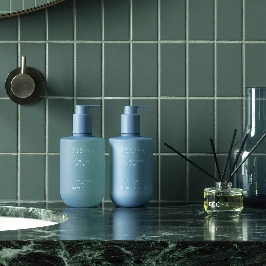 Ecoya Sandalwood & Amber Hand & Body Lotion med matchande handtvål och doftpinnar i badrum