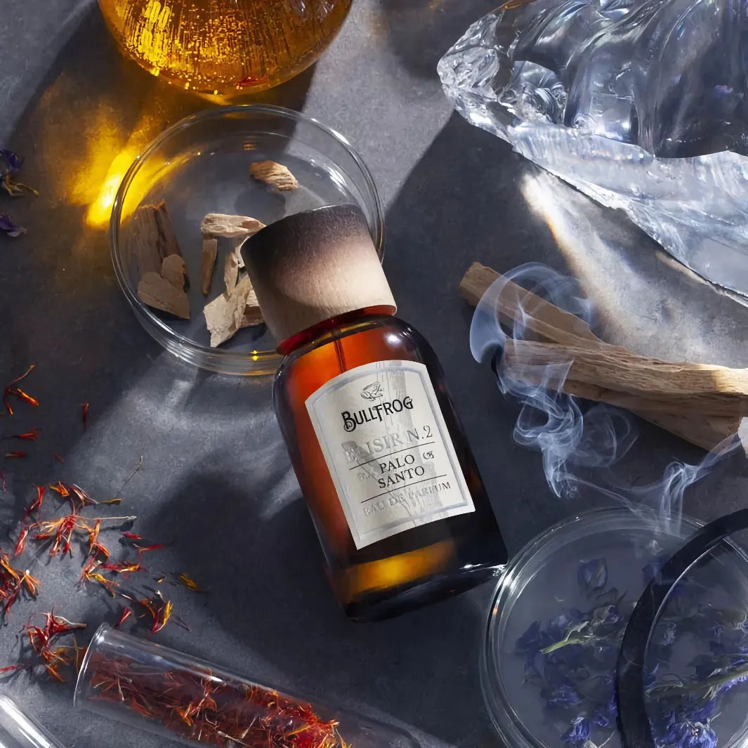 Bullfrog Elisir N.2 Palo Santo EdP omgiven av sina doftnoter med palo santo-träbitar, saffran och örter
