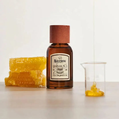 Bullfrog Elisir N.3 Dark Honey Eau de Parfum 100 ml bredvid honungskaka och glasbehållare – exklusiv parfym från Bullfrog