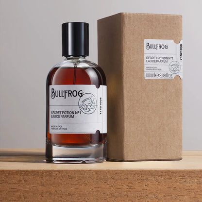 Bullfrog Secret Potion N°1 Eau de Parfum med ask – parfymflaska på 100 ml bredvid originalförpackning i brunt papper.