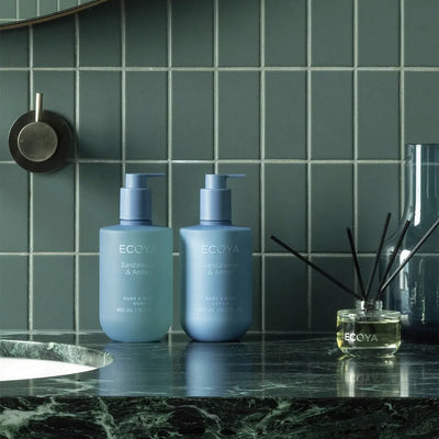 Ecoya Sandalwood & Amber Hand & Body Lotion med matchande handtvål och doftpinnar i badrum
