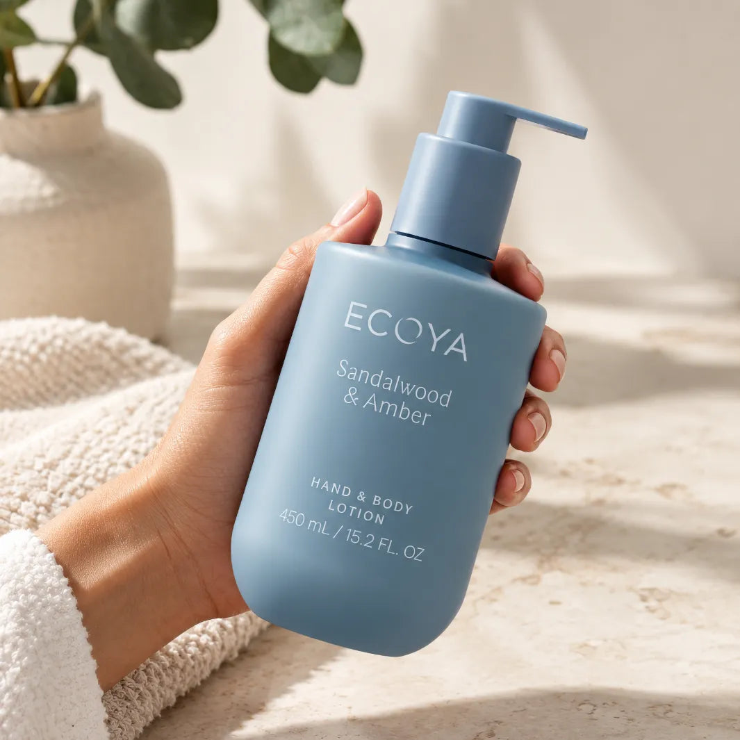 Ecoya Sandalwood & Amber Hand & Body Lotion 450 ml i blå pumpflaska som hålls i handen