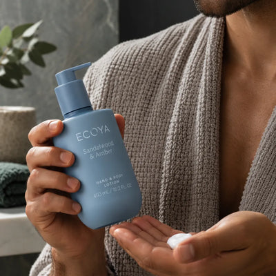 Man med Ecoya Sandalwood & Amber Hand & Body Lotion 450 ml och återfuktande kroppslotion i handflatan